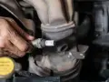 Mechanik trzyma w dłoni sondę lambda, przygotowując ją do czyszczenia.