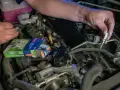 Mechanik wymienia świece zapłonowe w silniku, być może w celu rozwiązania problemu DTC P0300 w Volkswagenie.