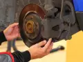 Mechanik sprawdza klocki hamulcowe, dotykając zacisku i tarczy hamulcowej.