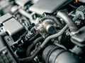 Wnętrze silnika z widocznym elementem, który może być częścią cylindra, otoczony przewodami i innymi komponentami.