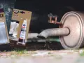 Zardzewiały tłumik z widoczną dziurą, obok taśma naprawcza Bandex i cement do tłumików K2 MEFIX.