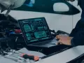Diagnostyka komputerowa samochodu cena: mechanik analizuje dane z laptopa dotyczące elektrycznego pojazdu.