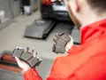 Mechanik trzymający zużyte klocki hamulcowe w warsztacie samochodowym.