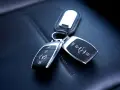 Dwa kluczyki samochodowe Mercedes-Benz z immobilizerem, leżące na skórzanym siedzeniu.