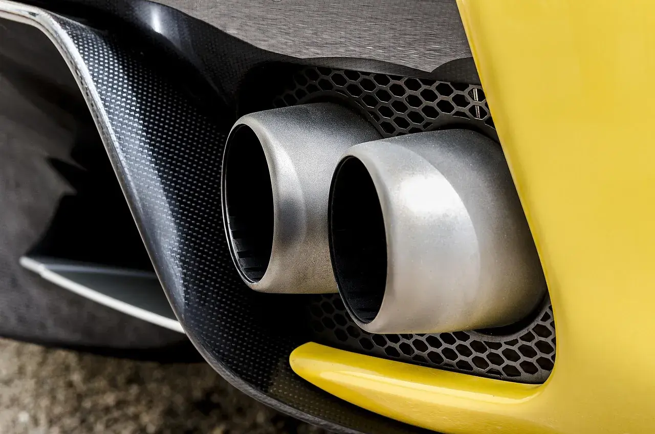 Podwójne końcówki wydechu sportowego samochodu. Wygląda, jakby ten diesel kopcił na czarno, ale to tylko odbicie.