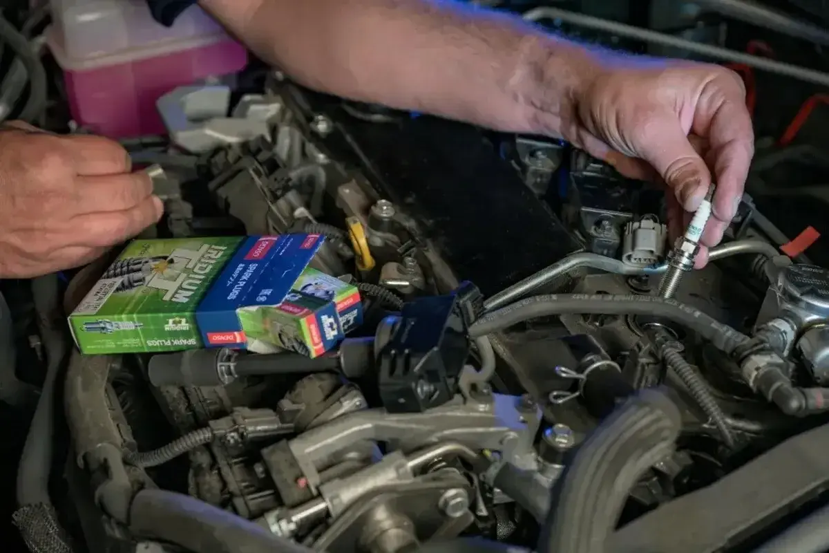 Mechanik wymienia świece zapłonowe w silniku, być może w celu rozwiązania problemu DTC P0300 w Volkswagenie.