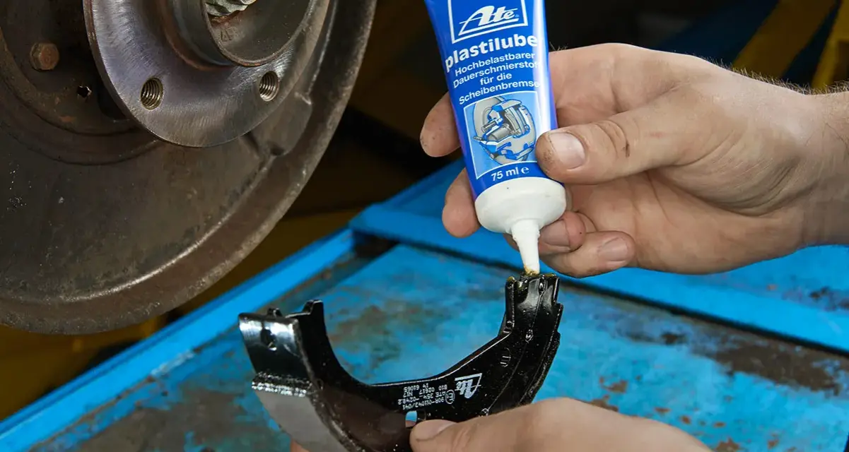 Mechanik nakłada smar ATE Plastilube na szczęki hamulcowe. To właściwy smar do tłoczków hamulcowych, zapewniający płynne działanie układu.