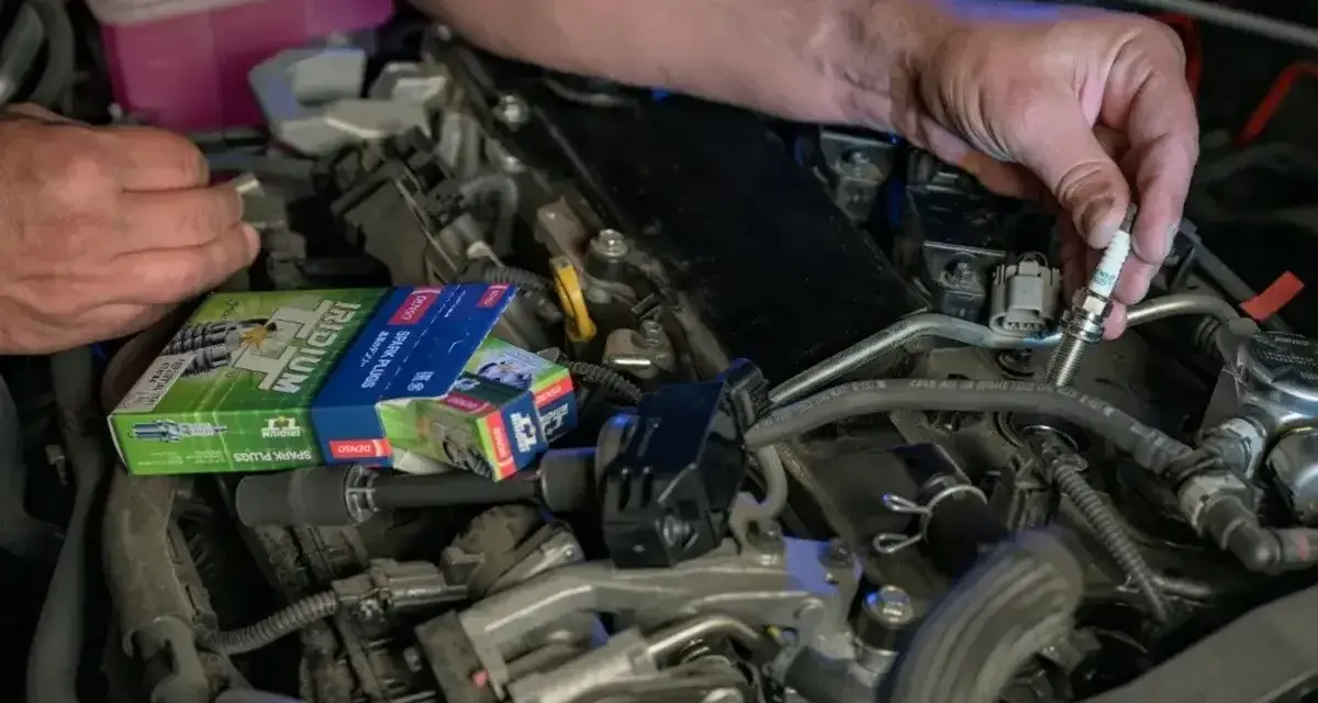 Mechanik wymienia świece zapłonowe w silniku, być może w celu rozwiązania problemu DTC P0300 w Volkswagenie.