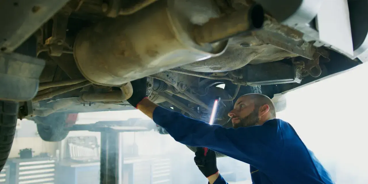 Mechanik bada podwozie Opla, szukając przyczyny błędu DTC P0420.