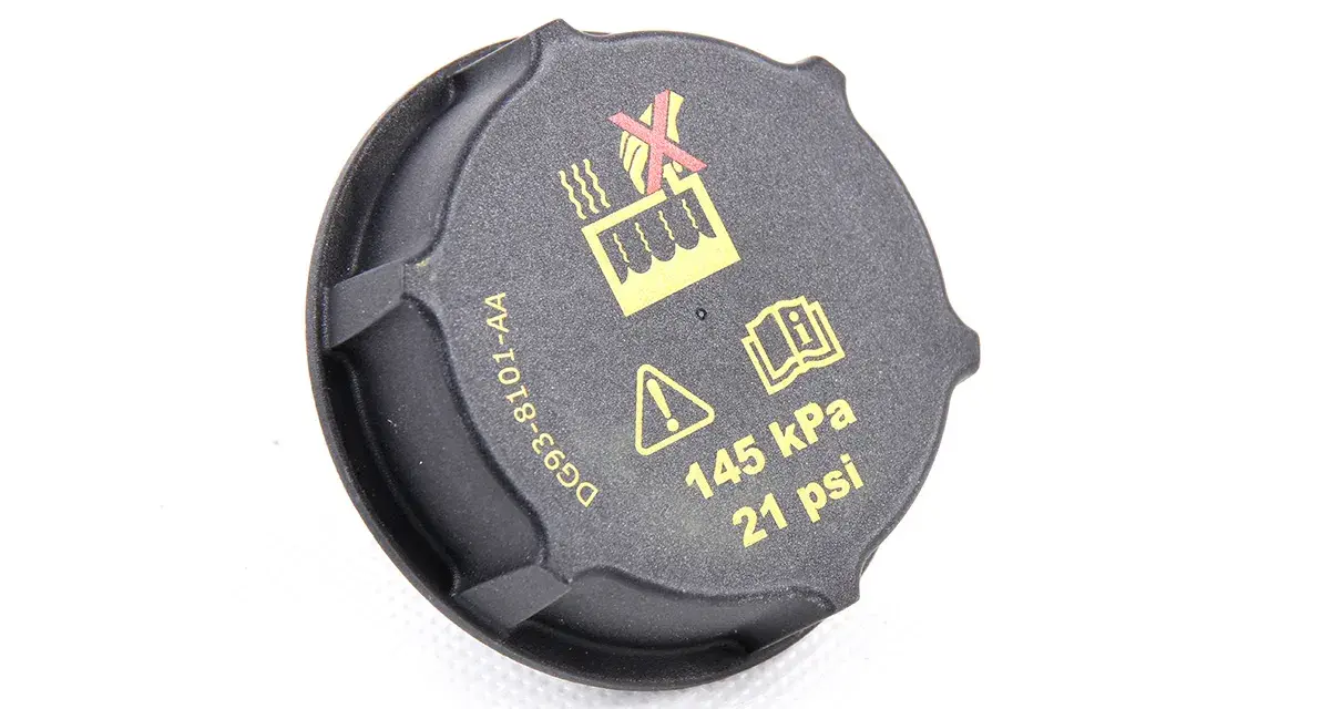 Czarne oznaczenie wlewu płynu do chłodnicy z symbolami ostrzegawczymi i informacją o ciśnieniu 145 kPa (21 psi).