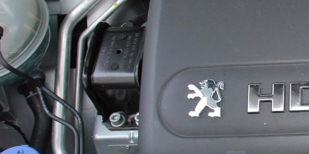 Elementy silnika, w tym poduszka silnika, gotowe do wymiany. Widoczny symbol Peugeot.