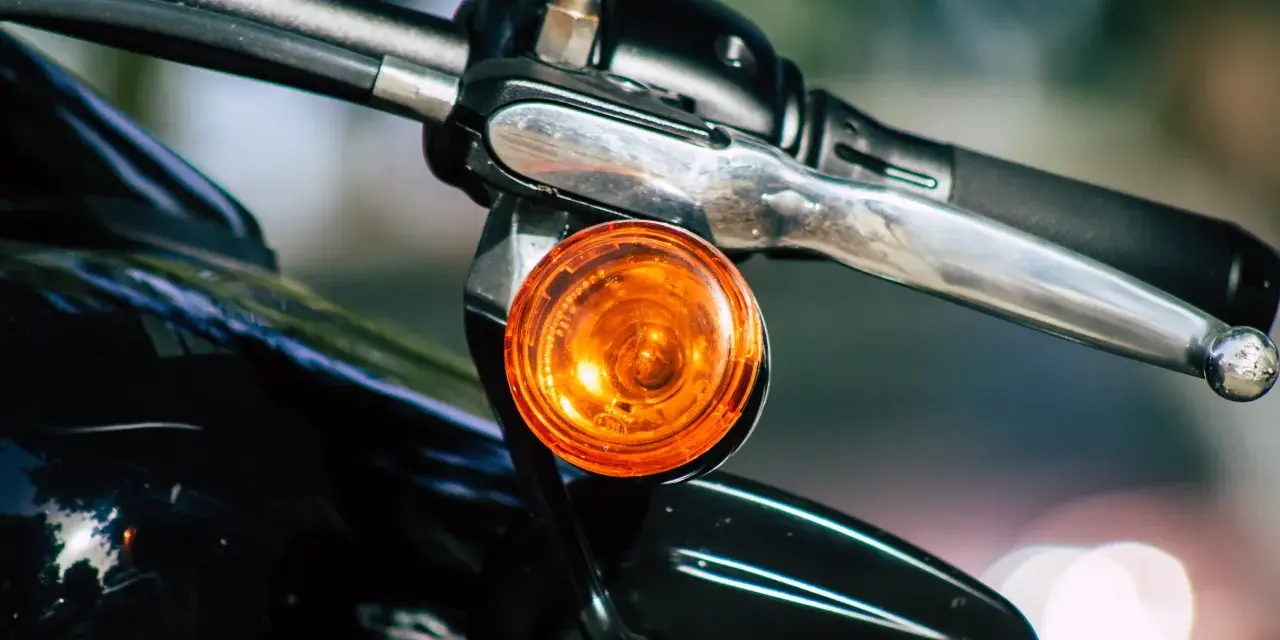 Pomarańczowy kierunkowskaz motocykla, gotowy do sygnalizowania skrętu.