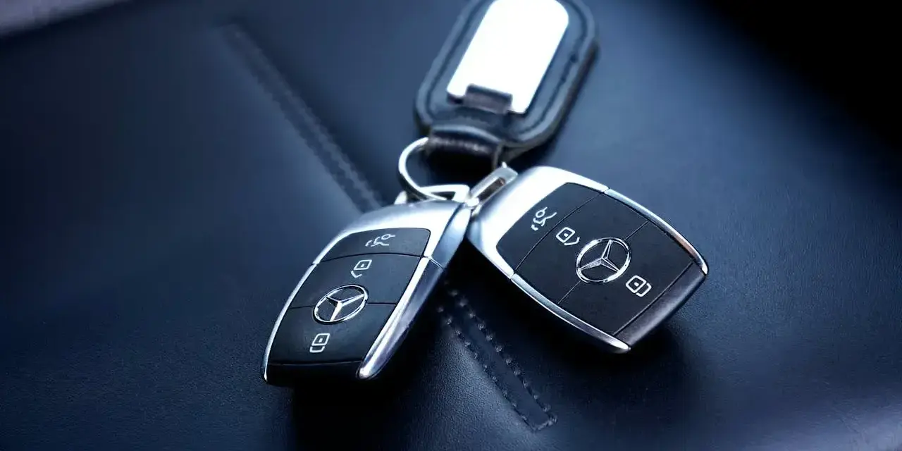 Dwa kluczyki samochodowe Mercedes-Benz z immobilizerem, leżące na skórzanym siedzeniu.