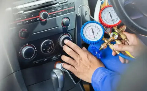 Mechanik sprawdza ile czynnika do klimatyzacji pozostało w samochodzie, używając manometrów.