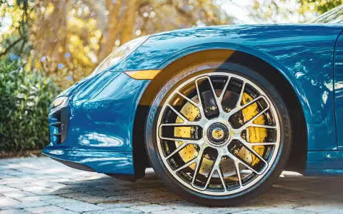 Błękitne Porsche z żółtymi zaciskami hamulcowymi i wieloramiennymi felgami. To jest et felgi, które dodają sportowego charakteru.
