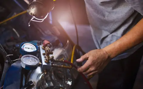 Mechanik sprawdza manometry układu klimatyzacji. Objawy zatarta sprężarka klimatyzacji mogą być widoczne na wskaźnikach.