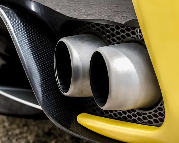 Podwójne końcówki wydechu sportowego samochodu. Wygląda, jakby ten diesel kopcił na czarno, ale to tylko odbicie.