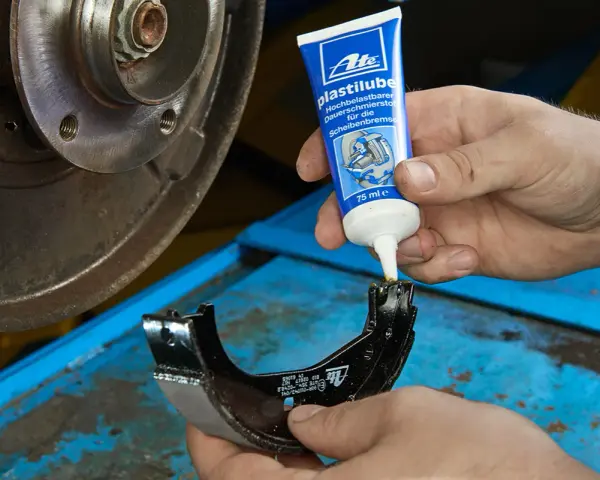Mechanik nakłada smar ATE Plastilube na szczęki hamulcowe. To właściwy smar do tłoczków hamulcowych, zapewniający płynne działanie układu.