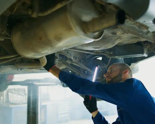 Mechanik bada podwozie Opla, szukając przyczyny błędu DTC P0420.
