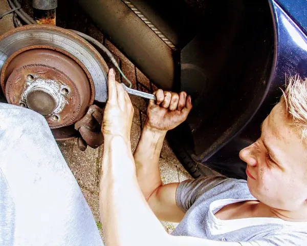 Mechanik z kluczem przy kole samochodu, wymiana łożyska.