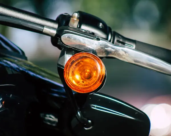 Pomarańczowy kierunkowskaz motocykla, gotowy do sygnalizowania skrętu.