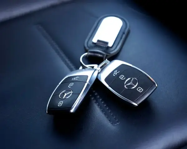 Dwa kluczyki samochodowe Mercedes-Benz z immobilizerem, leżące na skórzanym siedzeniu.