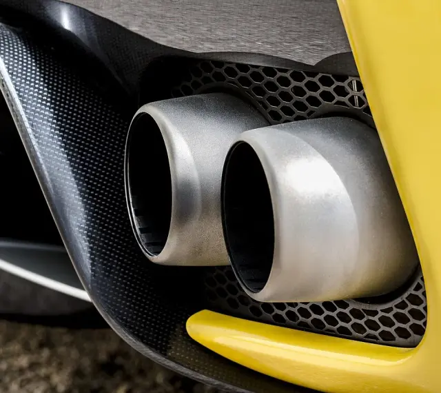 Podwójne końcówki wydechu sportowego samochodu. Wygląda, jakby ten diesel kopcił na czarno, ale to tylko odbicie.