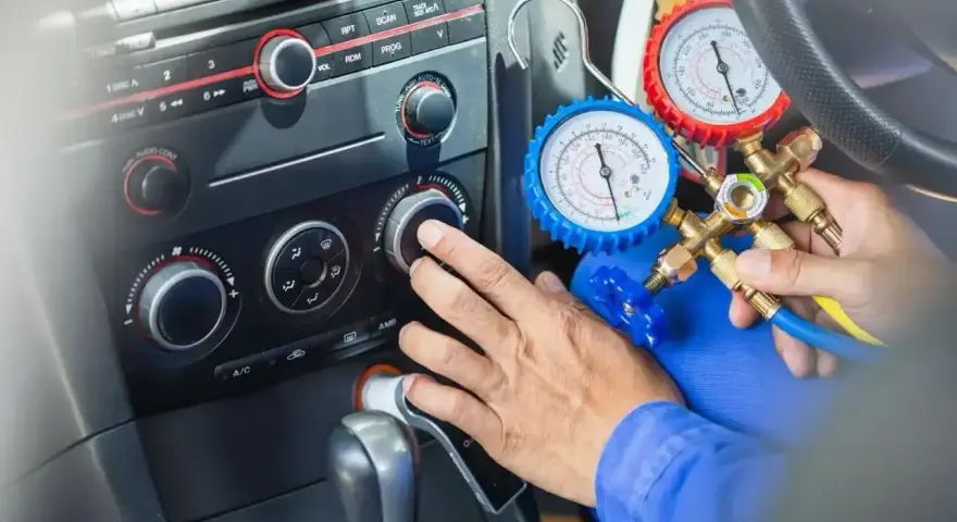Mechanik sprawdza ile czynnika do klimatyzacji pozostało w samochodzie, używając manometrów.