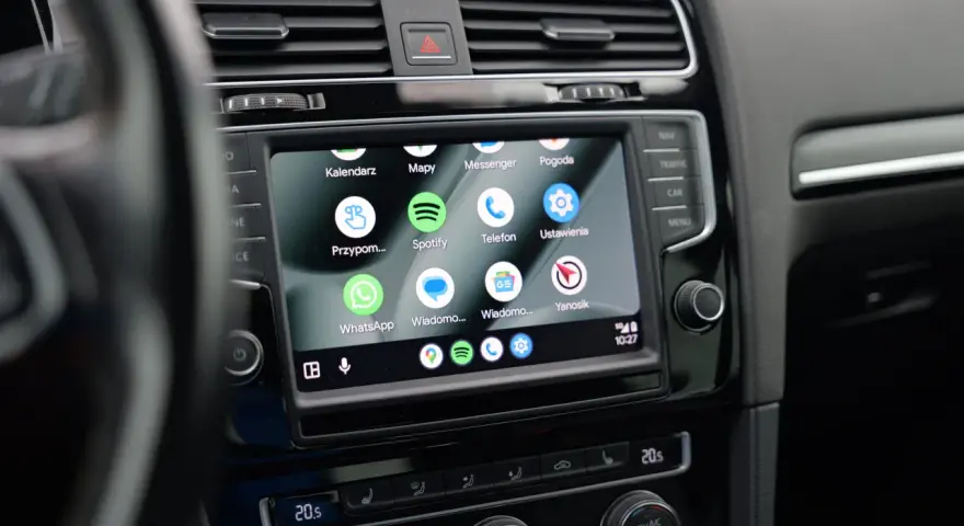 Ekran samochodu z widoczną aplikacją Android Auto, wyświetlającą ikony Kalendarz, Mapy, Spotify, WhatsApp i inne.