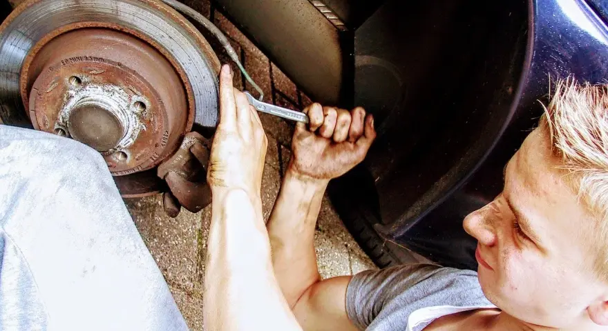Mechanik z kluczem przy kole samochodu, wymiana łożyska.