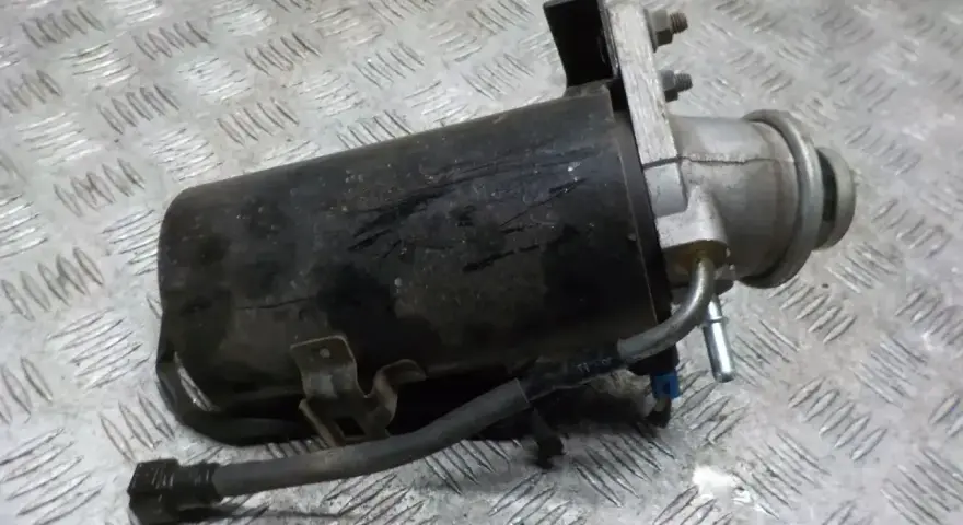 Filtr paliwa z widocznymi przewodami i mocowaniem na metalowym tle.