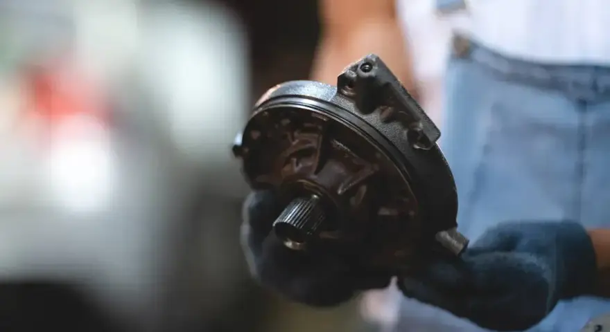 Mechanik trzyma element serwa hamulcowego. Objawy awarii mogą być różne, np. twardy pedał hamulca.