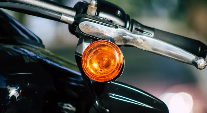 Pomarańczowy kierunkowskaz motocykla, gotowy do sygnalizowania skrętu.