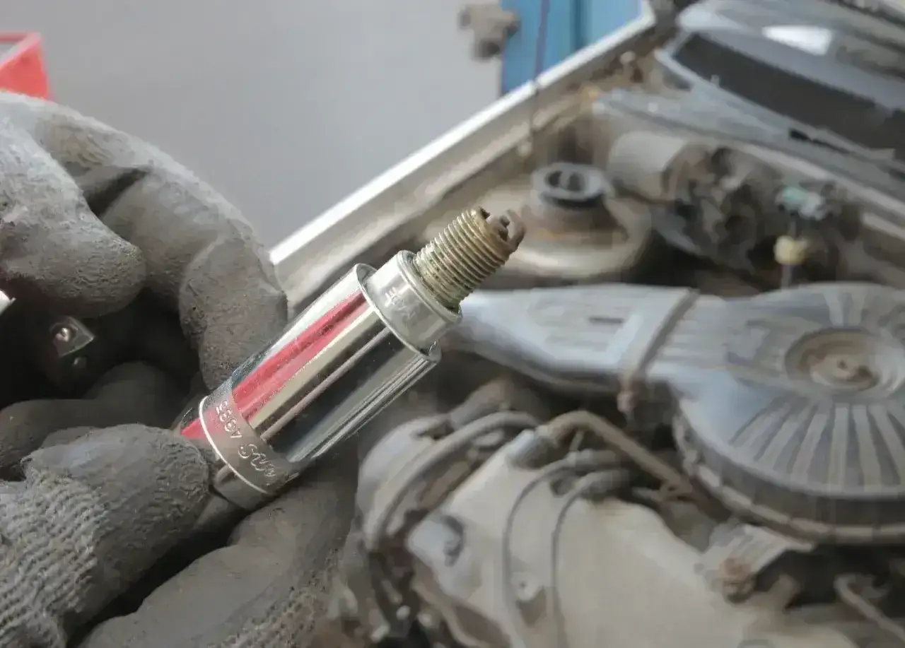 Ręka w rękawicy trzyma świecę zapłonową, potencjalnie związaną z błędem dtc p0301 w BMW.