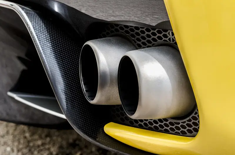 Podwójne końcówki wydechu sportowego samochodu. Wygląda, jakby ten diesel kopcił na czarno, ale to tylko odbicie.