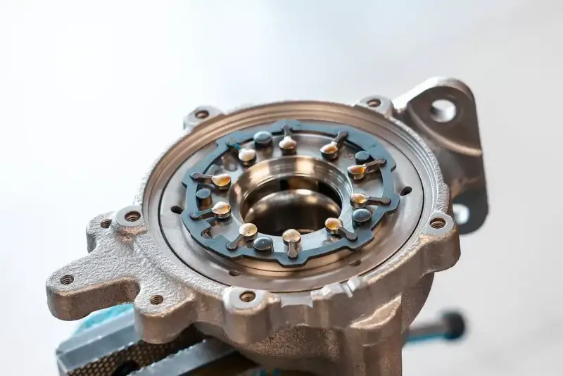 Metalowa obudowa turbosprężarki z widocznym mechanizmem kierownic spalin, kluczowym dla działania biturbo.
